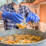 Person pouring liquid into large tub of sliced citrus